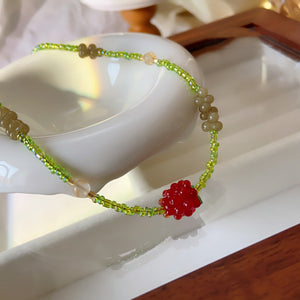 Cherry beaded necklace styled on a neutral background