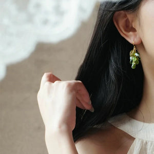 Green glass grape cluster dangle earring shown worn on an ear, displaying its size and drape