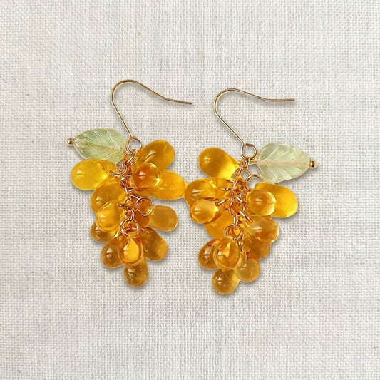 Close-up of handmade gold grape earrings featuring translucent glass beads and 14k gold plated vines