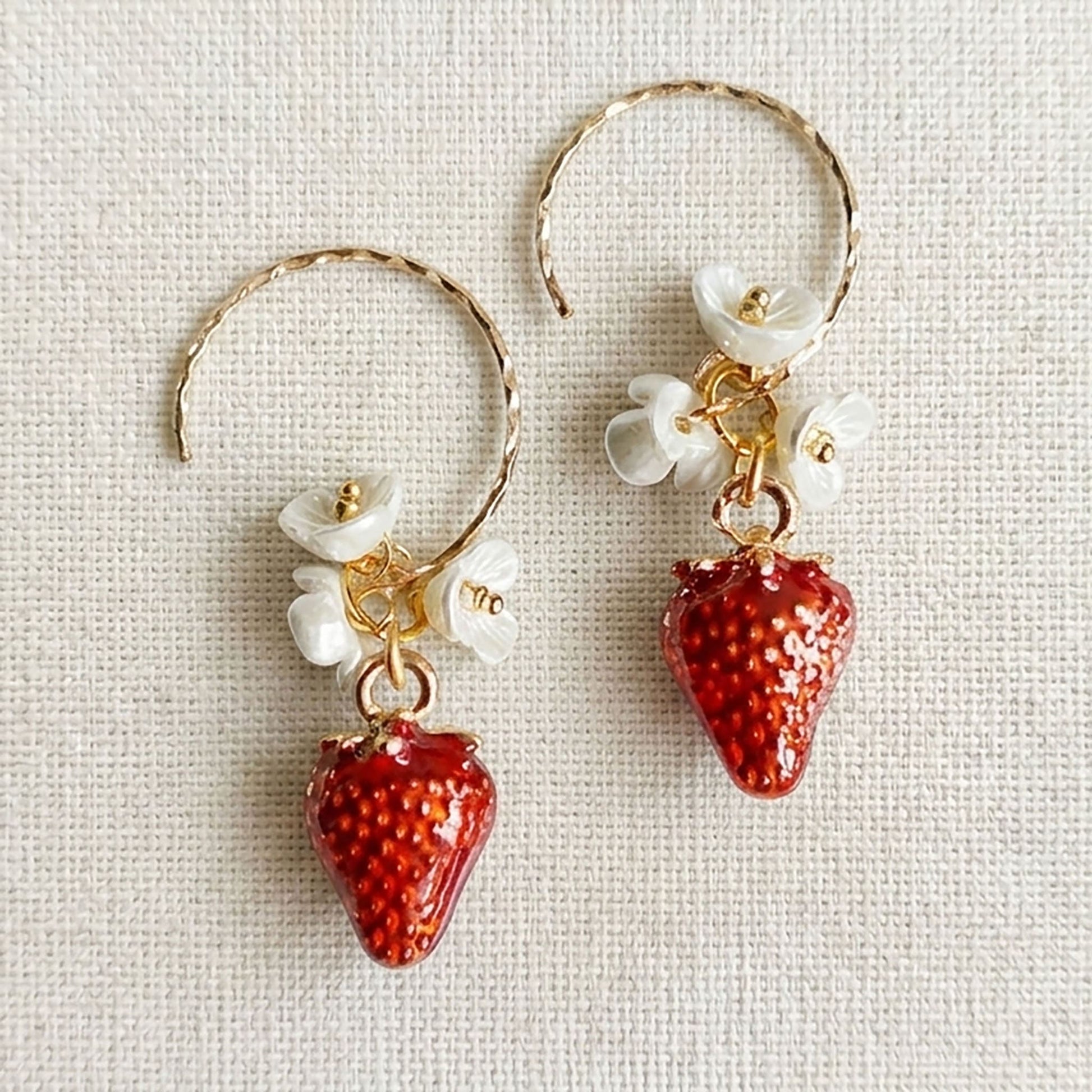 Close-up of handmade red glass strawberry earrings with green seed bead caps