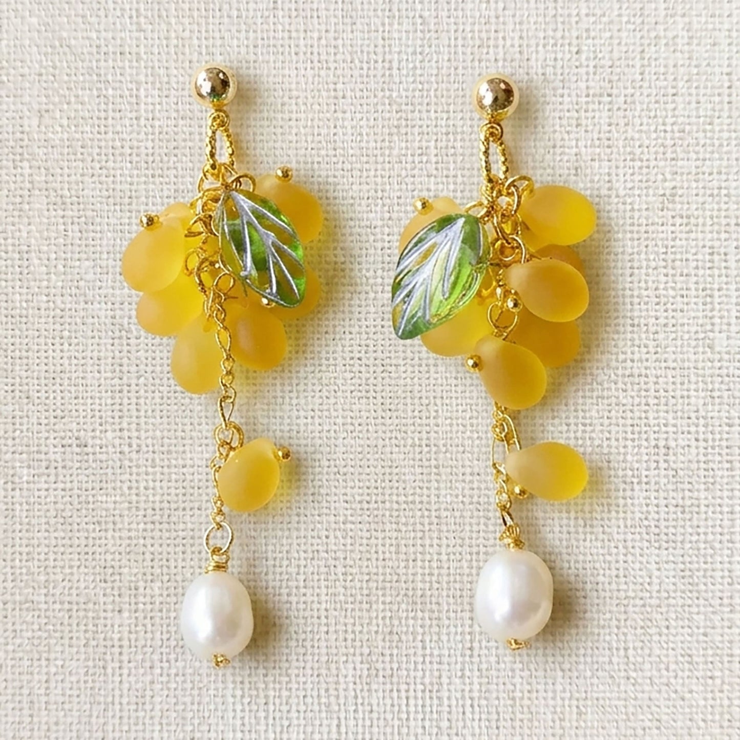 Close-up of yellow grape earrings featuring translucent Czech glass beads and gold-plated hooks