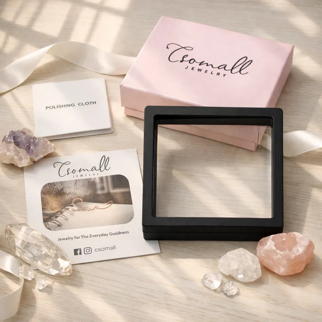 Csomall Jewelry gift packaging set with pink jewelry box, polishing cloth, branding card and decorative crystals, elegant flat‑lay presentation for women’s jewelry brand