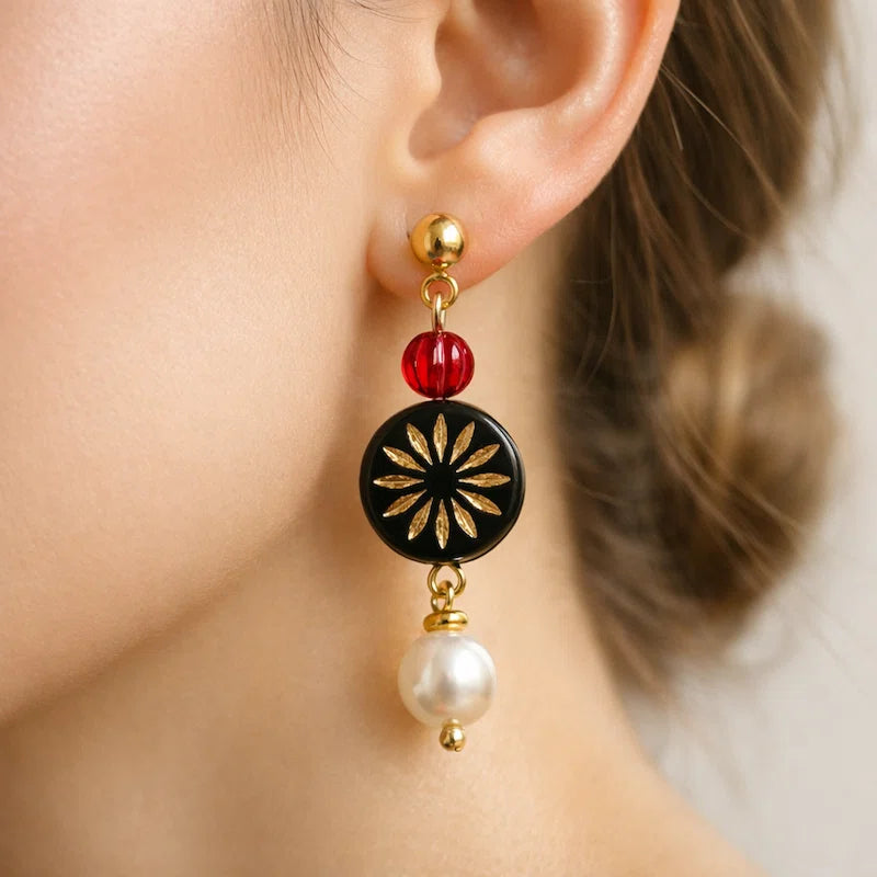 Handmade earrings with red bead, black gold floral medallion and white pearl drop worn by model, elegant jewelry for women