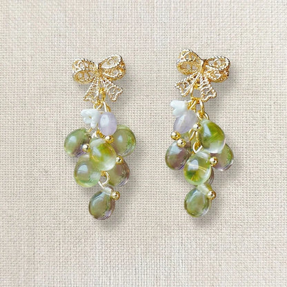 Handmade grape‑inspired earrings with gold bow, green and purple translucent beads and pearl accents, elegant Western‑style jewelry for women in the US and Europe