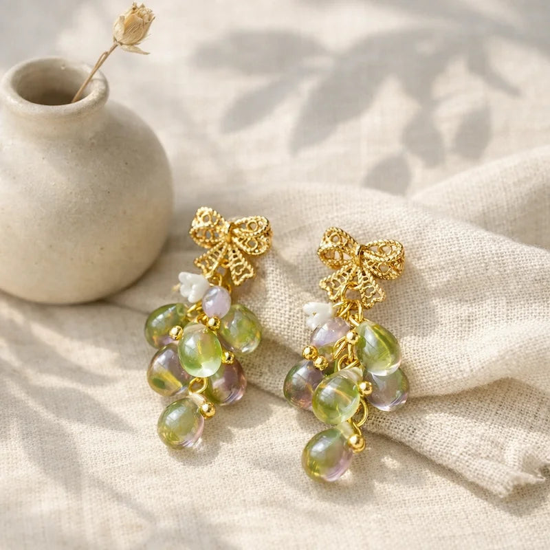 Handmade grape‑inspired earrings with gold bow, green and purple translucent beads and white flower accents, elegant Western‑style jewelry for women in the US and Europe