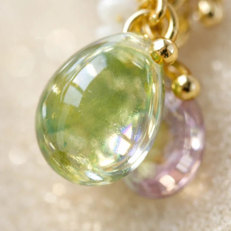 “Handmade jewelry detail with green translucent teardrop bead, gold accents and purple glass highlight, elegant Western‑style accessory for women in the US and Europe