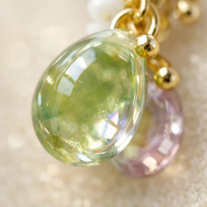 “Handmade jewelry detail with green translucent teardrop bead, gold accents and purple glass highlight, elegant Western‑style accessory for women in the US and Europe