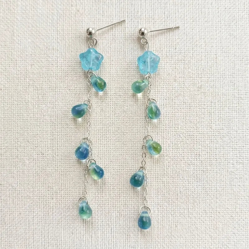 Handmade star‑drop earrings with blue translucent star bead, green and blue teardrop accents on silver chain, elegant Western‑style jewelry for women in the US and Europe