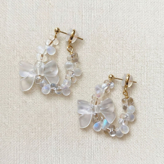 Pair of handcrafted Czech glass butterfly earrings with gold metallic bows on a white linen surface