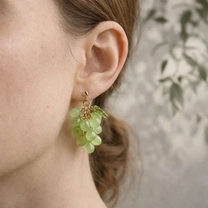 Woman wearing handmade Czech glass earrings with light green translucent grape beads and gold detailing, nature‑inspired bohemian jewelry for women in the US and Europe