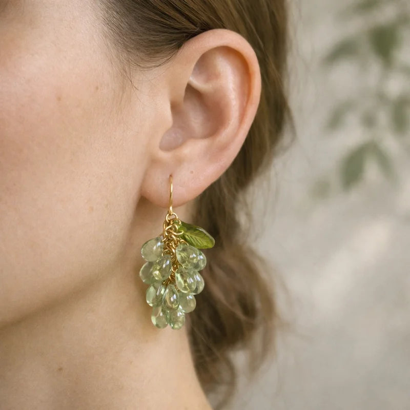 Woman wearing handmade Czech glass earrings with light green translucent grape beads and green leaf accents, nature‑inspired bohemian jewelry for women